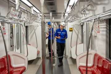 Maintenance crew in uniforms and helmets are methodically inspecting the interior of an empty train...