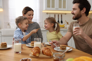 Happy family having fun during breakfast at table in kitchen