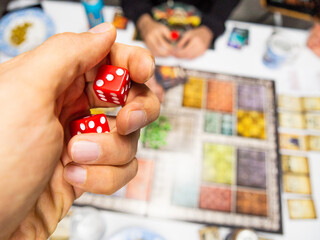 Hand with red dice on the game board with a three - 771874843