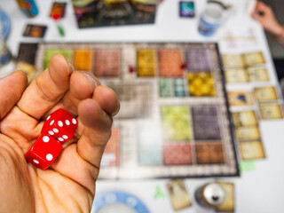 Hand with red dice on the game board with a three and two - 771875020
