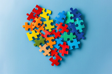 Colorful jigsaw puzzle heart shape on blue background. World Autism Awareness Day. Autism spectrum disorder family support concept