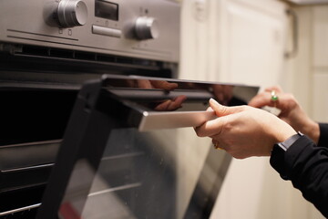 Naklejka premium Woman using the oven to cooking food in the kitchen