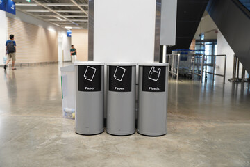 Trash cans with signs to classify waste types in building - obrazy, fototapety, plakaty
