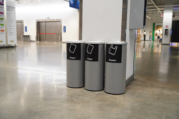 Trash cans with signs to classify waste types in building - obrazy, fototapety, plakaty