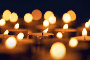 close up burning candles with defocused lights on black background 