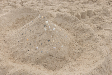 Children's entertainment sand castle with seashells on the beach abstract
