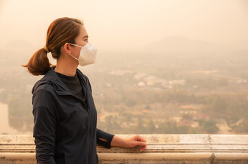 Asian woman wearing an N95 mask for protect bad air pollution. PM2.5 levels meaning the air quality...