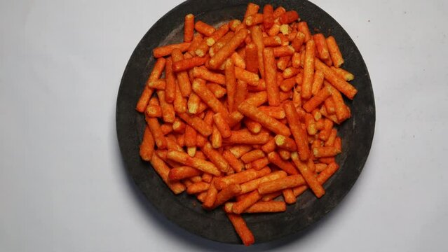 Crunchy cheese snacks on the wooden plate  with rotating background. Top view concept