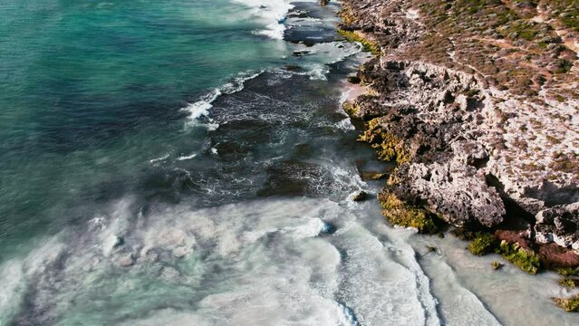 An expansive view from above capturing the contrast between rugged coastline and the clear, turquoise waters gently lapping at its edge.