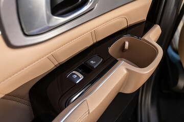 Side door buttons: window,  seat heating  adjustment buttons, door lock. Car inside..
