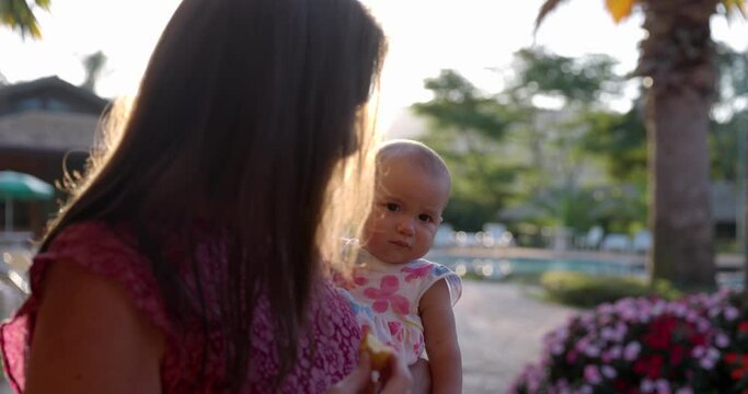 Grandmother holding young curious grand daugther in arms outdoors in tropical location