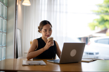 Smiling Woman Enjoying Coffee While Working on Laptop