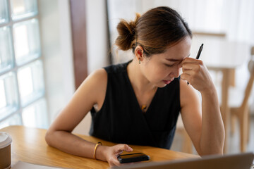 Stressed Businesswoman with Smartphone at Desk