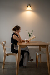 Contemplative Woman Enjoying Book in Minimalist Cafe