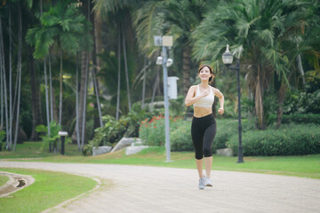 asian woman jogger running in green nature public park.