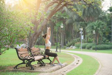 Woman jogger refreshing and sitting over bench in a park after running