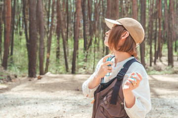 キャンプ場で虫除けスプレー・日焼け止めスプレーを使う女性
