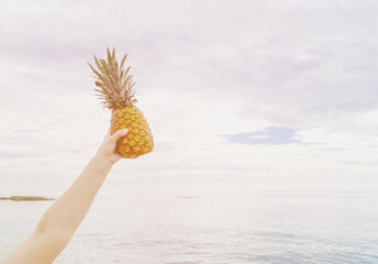 Someone holding a pineapple up in the air - Powered by Adobe