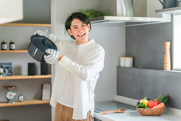 キッチンのHIコンロで煮込み料理をする若い男性（自炊・料理男子）
