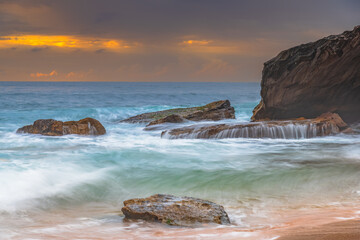 Sunrise at the seaside with rocks and beautiful diffused light by the rain clouds