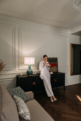 The image features a person wearing a white dress in an indoor setting, specifically in a living...