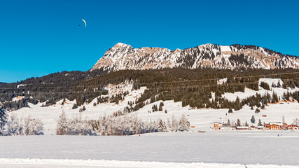 Alpine winter wonderland view with a paraglider near Tannheim, Reutte, Tyrol, Austria