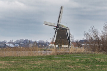 View of the historic thatched Veendermolen with miller's cottage on the bosom of the Weide Aa near the Dutch village of Roelofarendsveen against the background of a winter cloudy sky