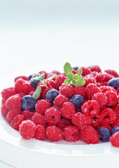 Raspberries and blueberries in a bowl over white background