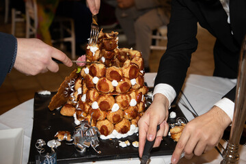 Dessert serving croquembouche with server hands