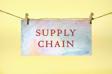 The words Supply Chain written on colored paper on a rope in front of a yellow background