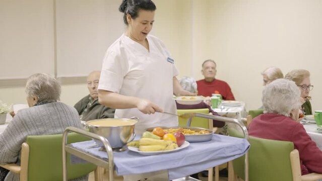 Friendly cook serving food to seniors in a nursing home