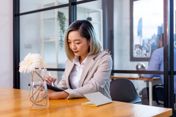 Portrait of Asian business CEO woman is working in office at the table with digital tablet and...
