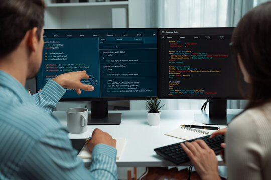 Team skilled developers program coding discussing creative website planning software project on two screen monitor's full stack data analyzing design at office with back side view concept. Postulate.