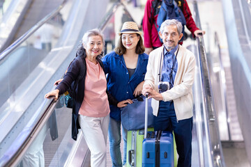 Group of Asian family tourist passenger with senior parent using escalator at the airport terminal for airline travel and holiday vacation concept