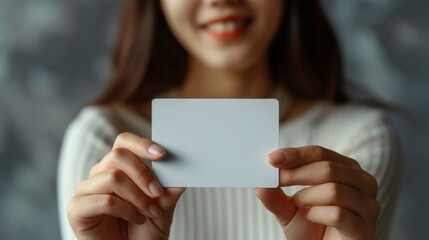 Mockup with beautiful manicured hands holding a 5 inches wide by 7 inches length, blank invitation card vertically, light background.