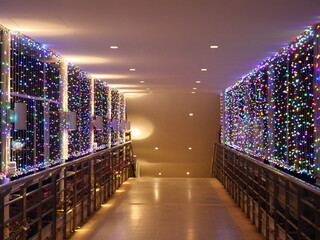 Nighttime shot of multi-colored flickering light bulbs hanging on a string of wires, decorated at...