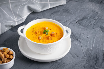 Pumpkin soup with croutons on grey background, with copy space for text