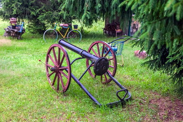 Homemade antique cannon close-up on the background of greenery in summer
