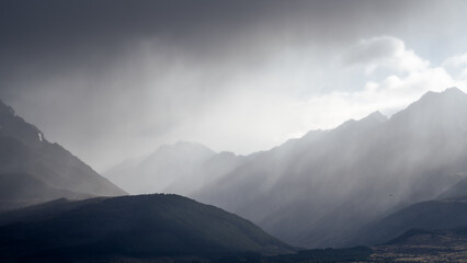 Storm with dark thick clouds approaching alpine landscape with mountain range and forest,New Zealand