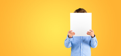 Boy hiding face with blank mock up banner, empty colored background