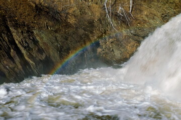 Spring landscape with waterfall and rainbow on the northern river with stone banks