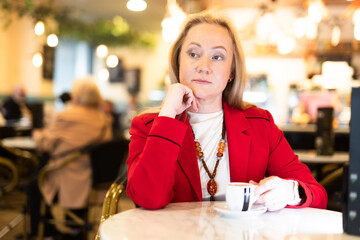 Portrait of stylishly dressed woman with cup of coffee in restaurant