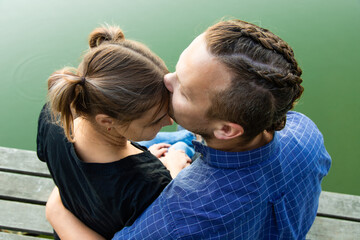 Beautiful, happy couple have fun on the background of nature. A handsome guy in a shirt gently hugs a smiling girl with blond hair. Lifestyle and travel concept.