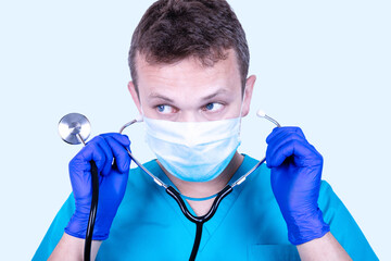 Doctor in a medical disposable mask puts on a stethoscope. Medical concept