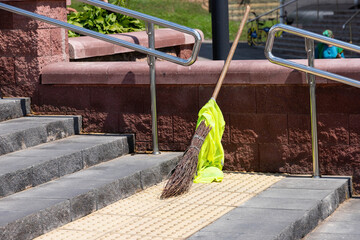 Broom, standing on the sidewalk, steps. The concept of a clean city. The problem of migrants,...