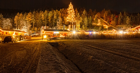 Christmas or x-mas market at night with the tallest living Christmas tree in Europe at Neukirchen,...