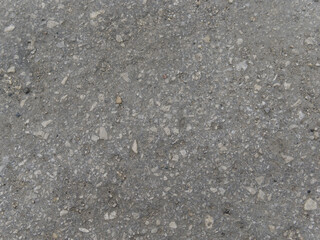 The texture of the gray cement wall with stones frozen inside. Close