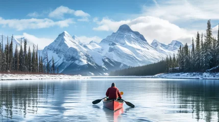 Foto op Canvas A man in a red canoe is paddling down a river in the mountains © liliyabatyrova