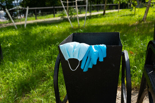 Thrown away medical gloves and protective masks in the trash bin after quarantine. Recycling and ecology concept.
