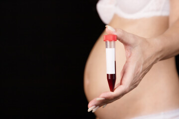 A pregnant woman holds a test tube of blood in front of her. Pregnancy, blood control in the...